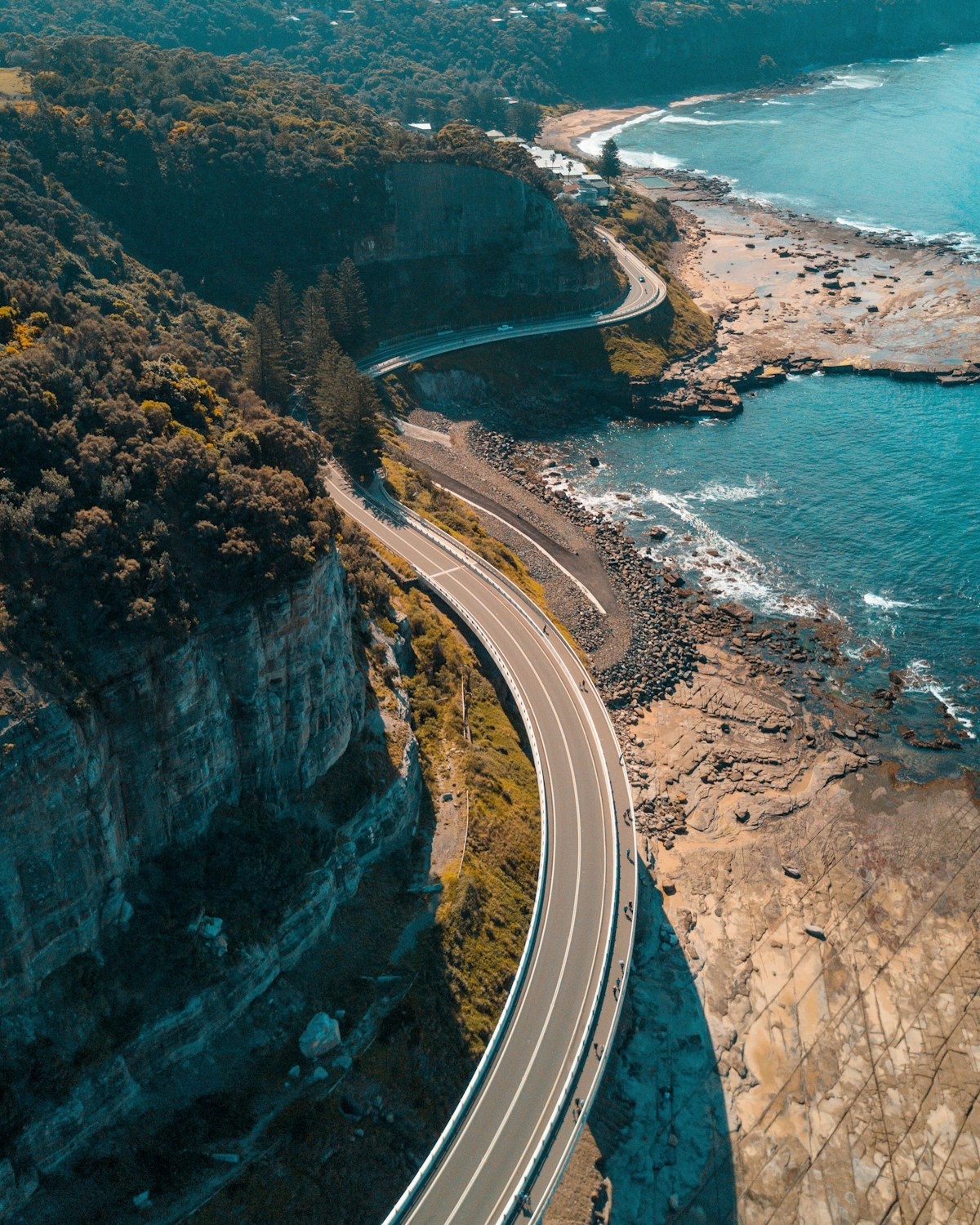 The Sea Cliff Bridge curving around a forested headland above the crashing Pacific on the New South Wales coast.