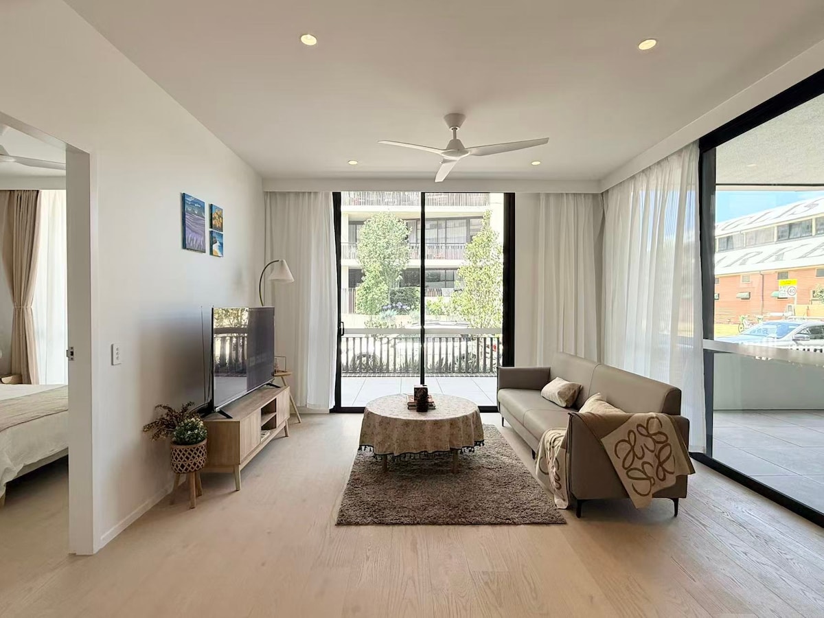 Bright modern living room in a two-bedroom Randwick apartment, with a sofa, balcony and large windows.
